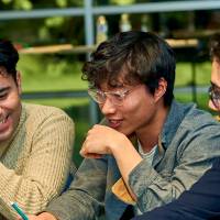 International Anchor Allies Winter 2026 First Mixer - group picture of three male student looking on a phone